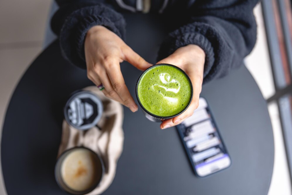 woman-holding-hands-trendy-green-matcha-drink-smartphone-top-view_169016-33945.jpg